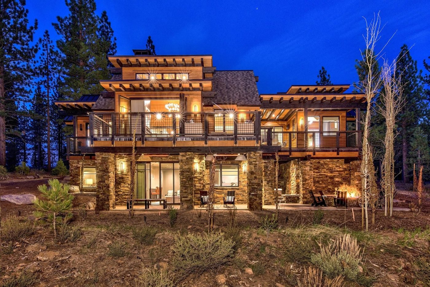 Exterior of a Pacaso mountain home at dusk with timber, stone, and lit decks