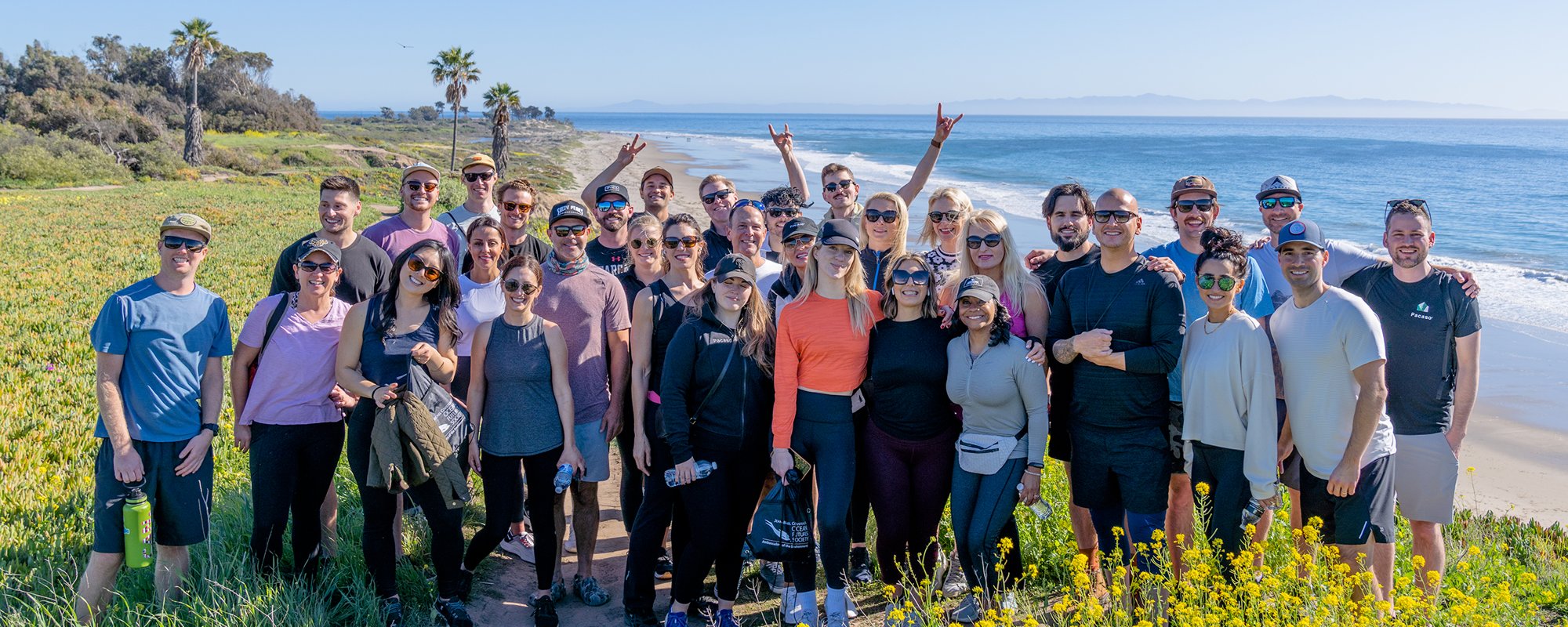 The full Pacaso sales team on a coastal bluff above the Pacific; Keenan is on the far right in a black Pacaso shirt