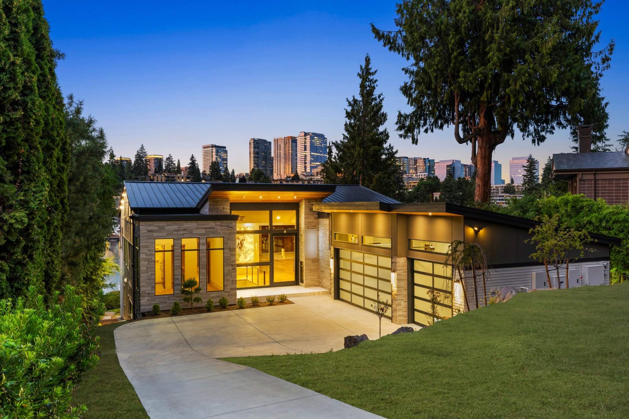 Modern custom home by The Custom Home Company at dusk with the Bellevue skyline behind