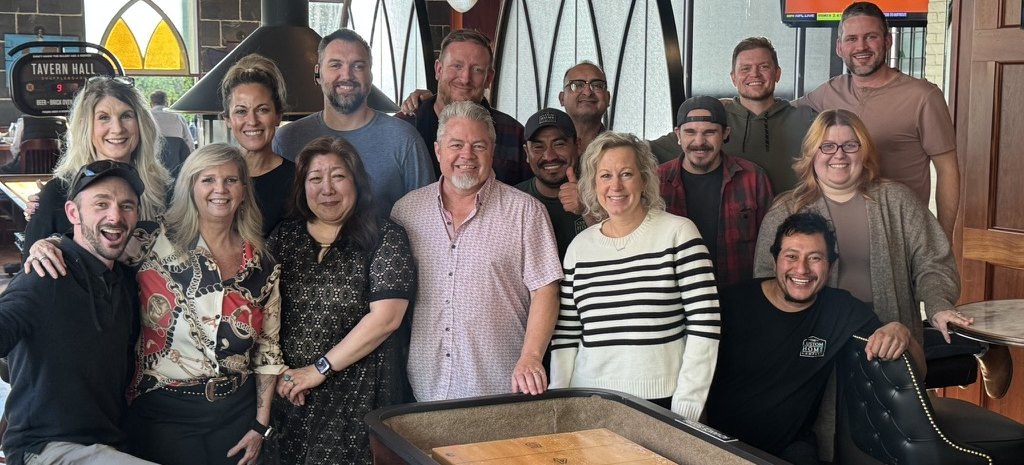 The Custom Home Company team gathered around a shuffleboard table
