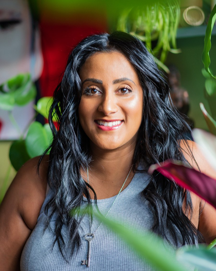 A portrait by West Sound Photography of a woman framed by green houseplants